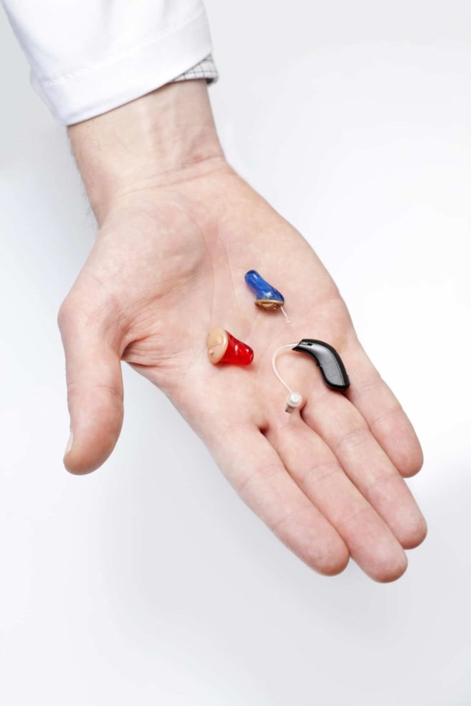 An audiologist holds three types of hearing aids in his hand in the St. Louis, MO area.
