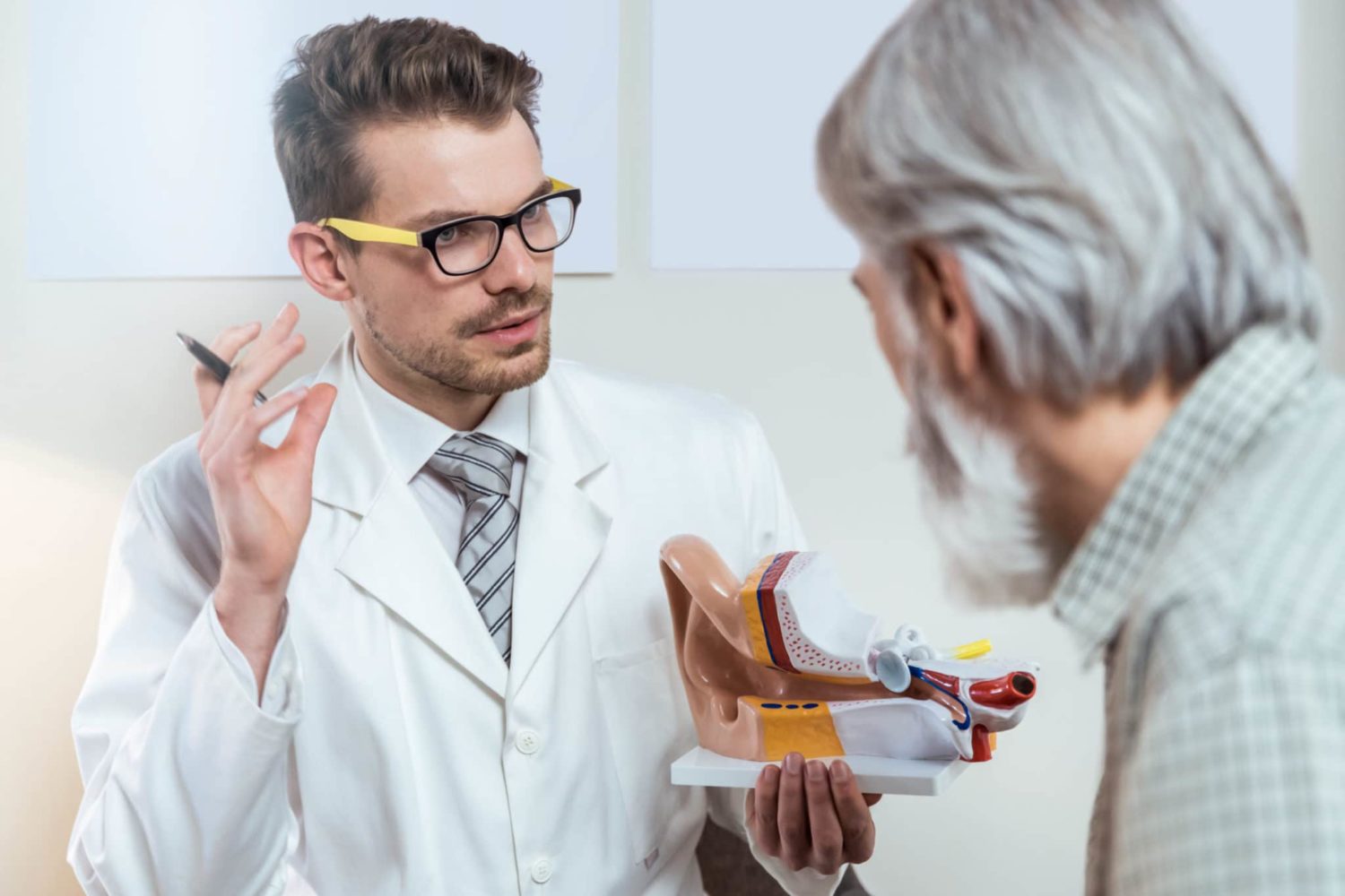 An audiologist shows a male patient a model of an ear at a hearing clinic in the St. Louis, MO area.